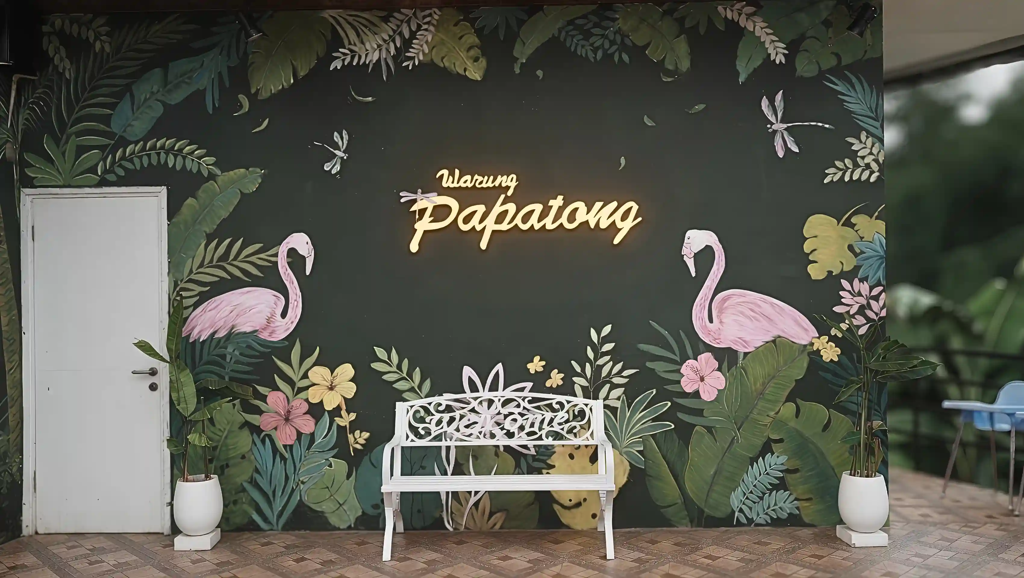 Spot welcome wall ikonik Warung Papatong dengan mural tropis artistik yang cocok untuk area foto pengunjung.