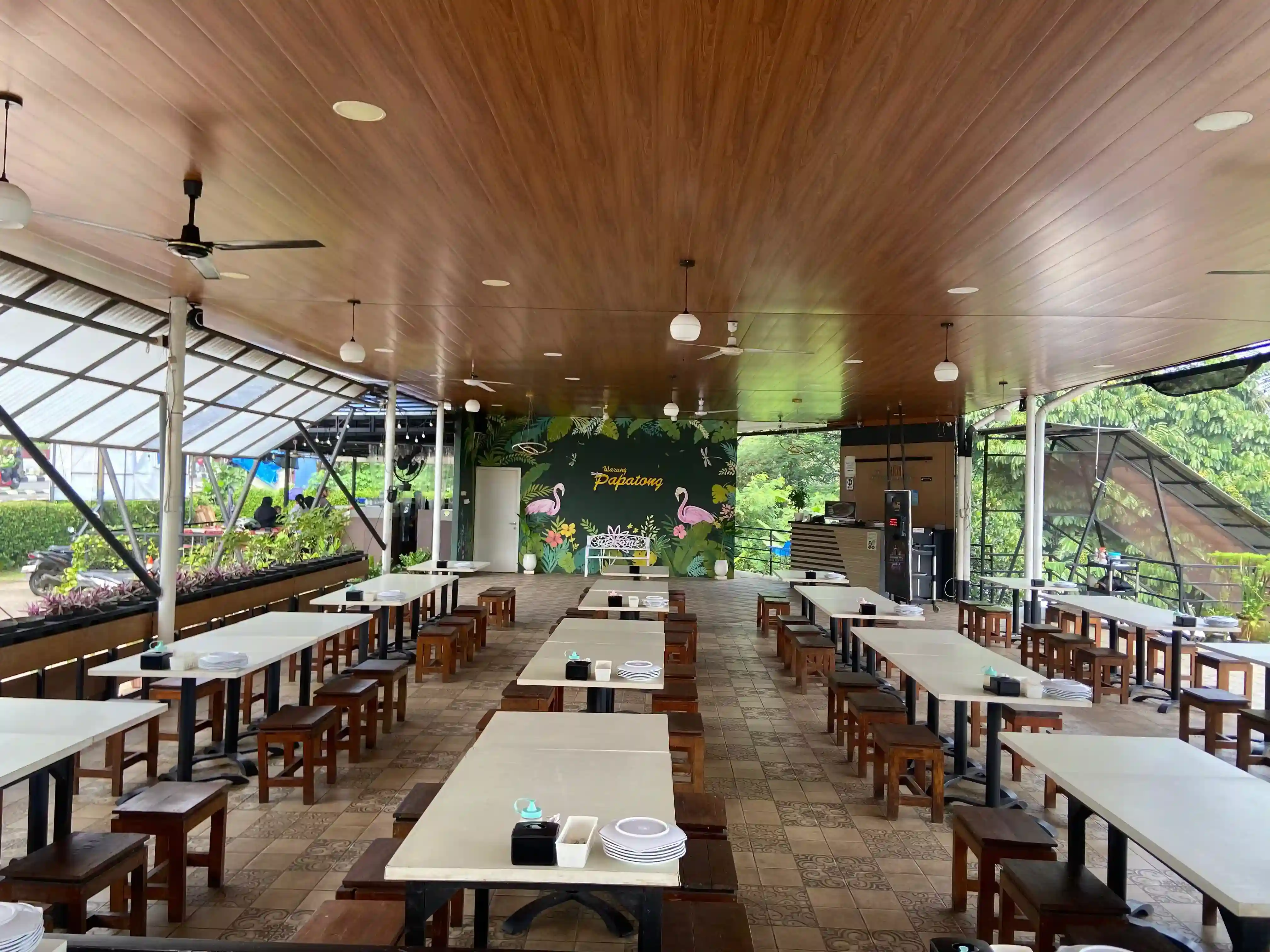 Area makan utama semi-outdoor dengan meja panjang luas dan nuansa angin sejuk dan pencahayaan alami.